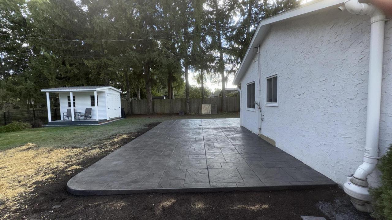Wide grey stamped concrete patio in a backyard