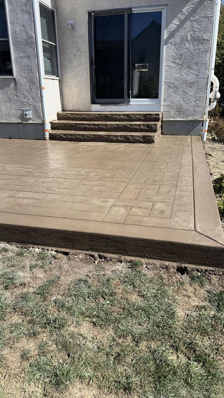 Tan stamped concrete patio with brown rock-face steps and border