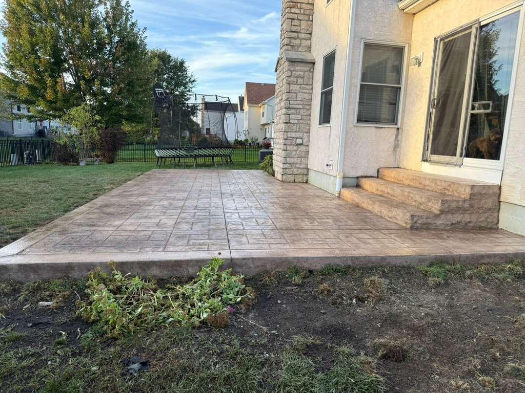 Tan stamped concrete patio at a stone-front home