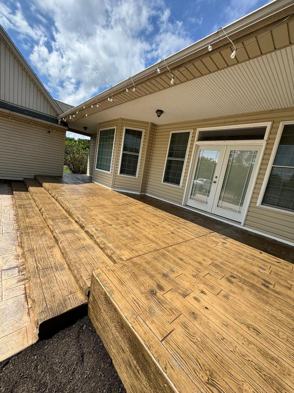 Wide wood plank stamped concrete patio with string lights