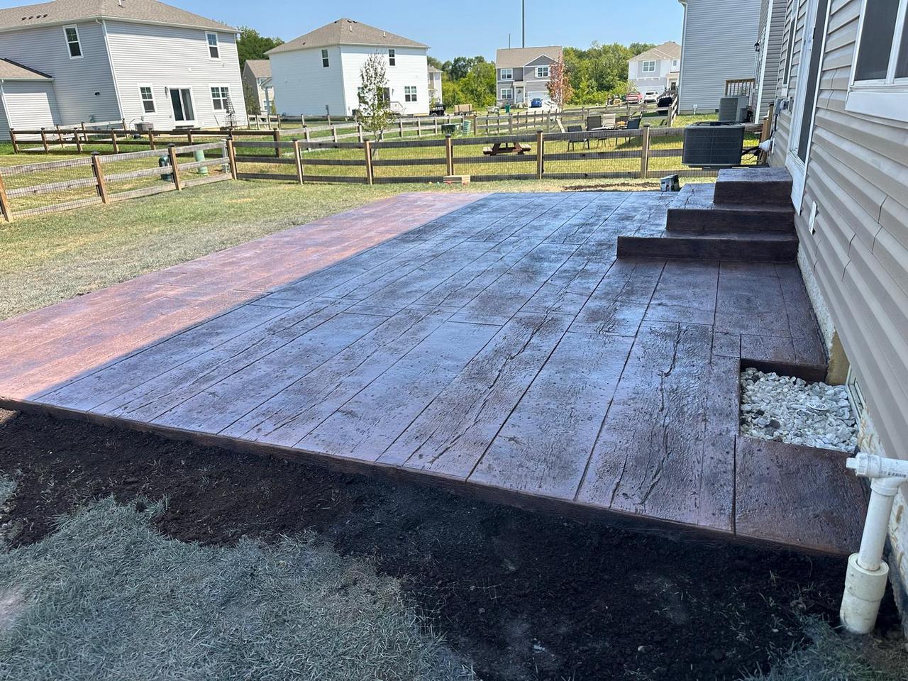 Wood plank stamped concrete patio with steps and open backyard