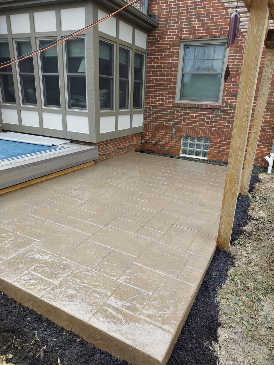 Tan stamped concrete pool deck beside a pergola