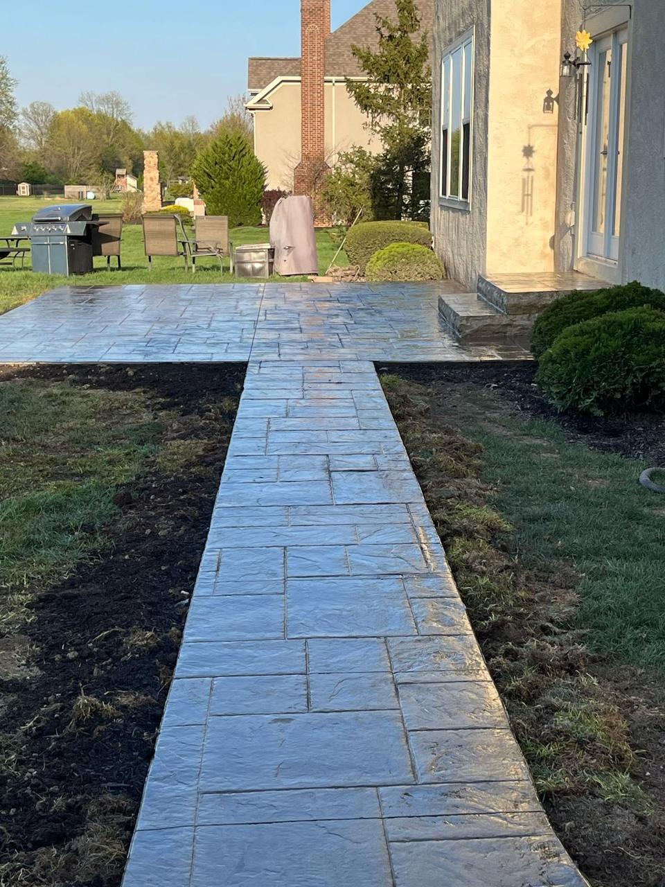 Stamped concrete walkway connecting a back patio to the yard