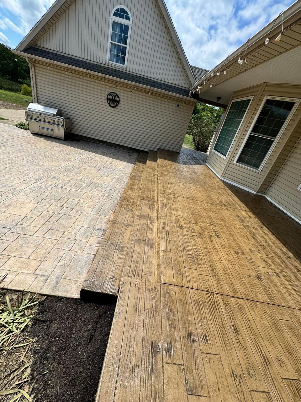 Wood plank stamped concrete beside ashlar slate patio with outdoor kitchen